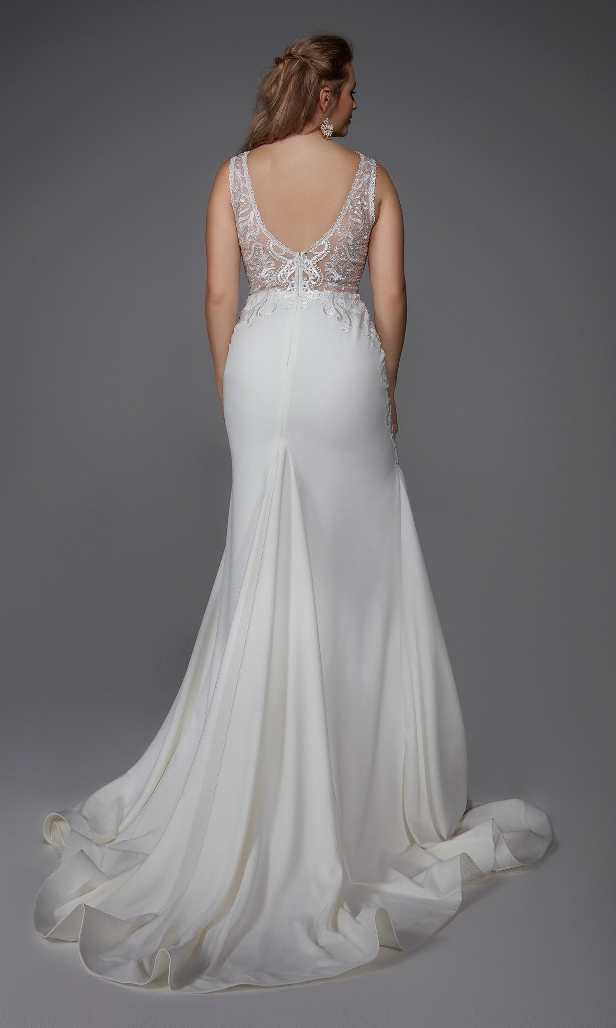 A woman faces away, wearing the Alyce 7016 long white dress featuring a sleeveless design, sheer lace back with button details, and a sweeping train set against a plain gray background.